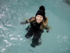Wetlook girl with winter clothes swims in the pool